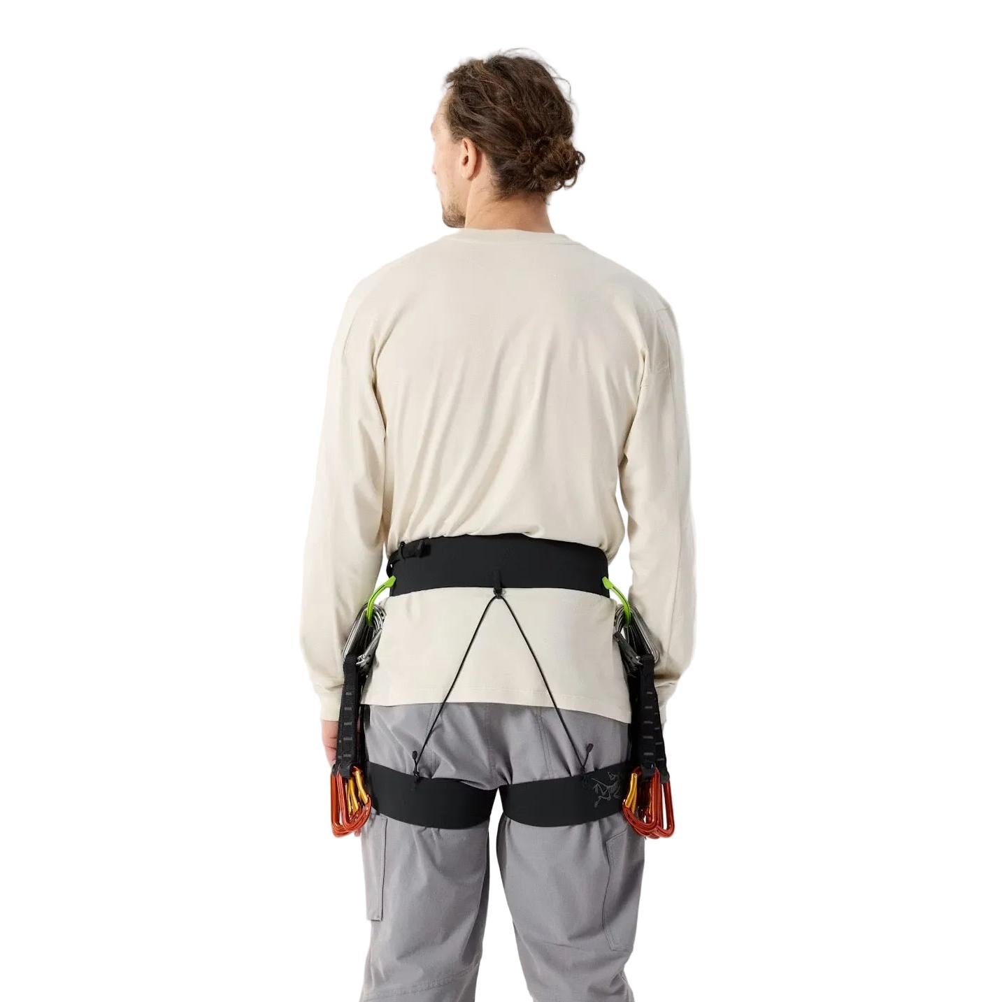 Person wearing arcteryx lithos climbing harness with a beige shirt and gray pants on a light background in the backside view